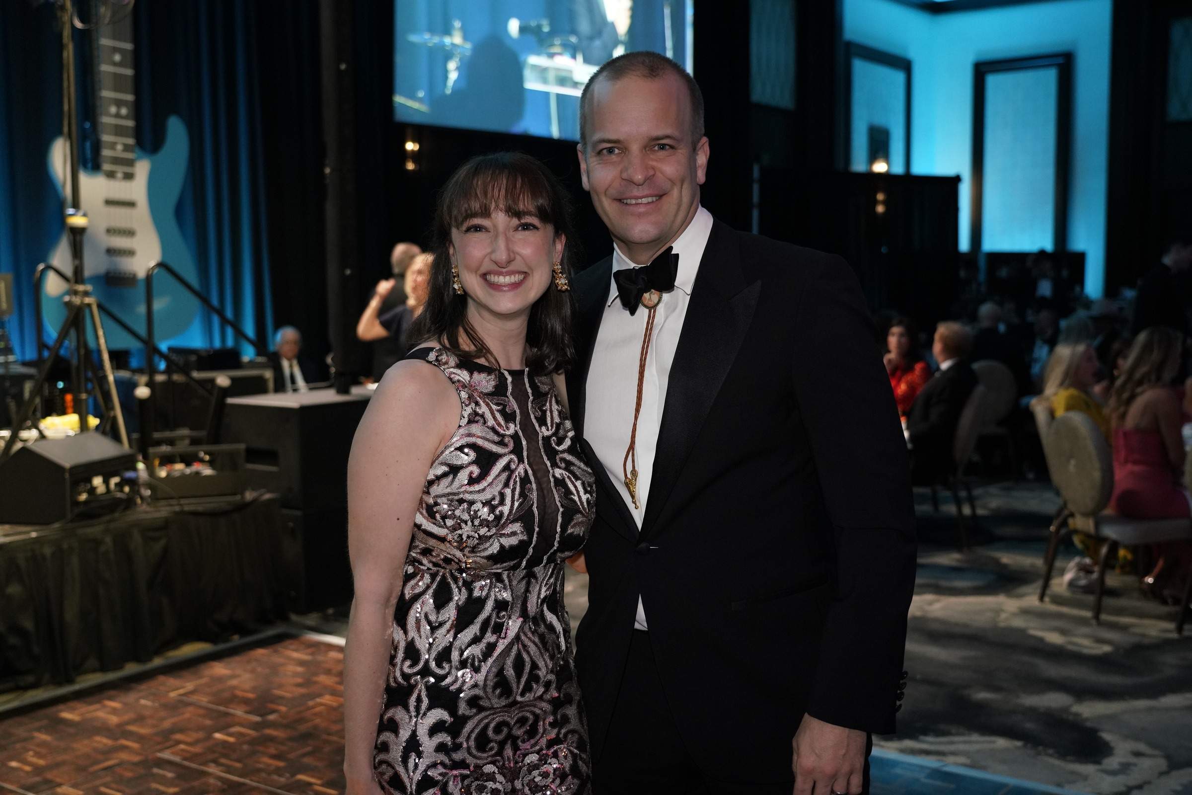Two adult guests posing together beside a stage at a formal ROCO event